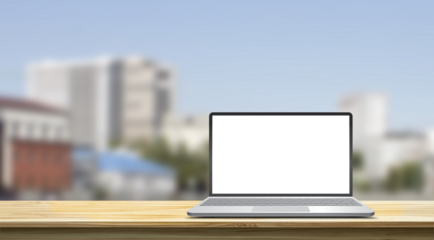 laptop with blank screen standing on the wooden table against the blurred city landscape, mock-up concept
