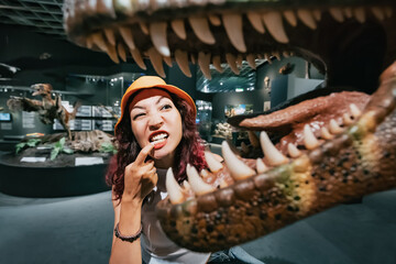 Funny tourist girl or a paleontologist student looks with interest at the open jaw with many large...