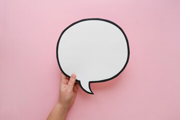 Speech bubble in hand on a pink background. Comic cloud with a place for text