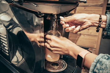 A girl squeezes fresh orange juice in a juicer in a supermarket
