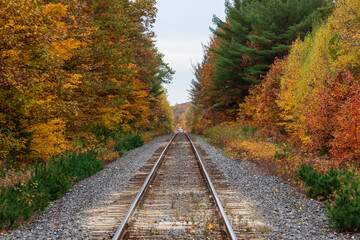 Fototapeta premium Sainte Ursule, Canada, 10-12-2022. Railway with fall colors in background near Sainte Ursule Waterfall. Canada.