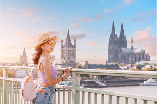 A tourist girl stands on the bridge over the Rhine River and admires the panoramic wonderful view of the Cologne Cathedral and cityscape