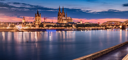 Panorama of illuminated Cologne or Koln Cathedral Dom and bridge over Rhine river in the twilight...