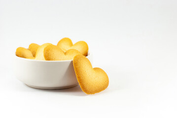 Heart-shaped biscuits in a white cup isolated on white background closeup, empty space for text. Valentine's day concept.