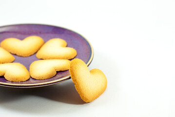 Heart-shaped biscuits on a ceramic plate isolated on white background, selective focus, and empty space for text. Valentine's day concept.