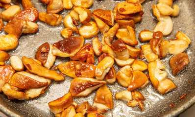 Fried mushrooms in oil in a frying pan.