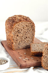 Fresh sliced rye bread on a wooden board. Healthy bread with sunflower seeds and flax on a white background.