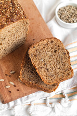 Slices of fresh rye bread close up with seeds on a wooden cutting board.
