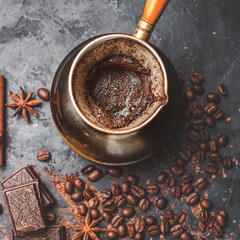 Fresh brewed coffee in the turkish jezva coffee pot on dark background with coffee beans and...