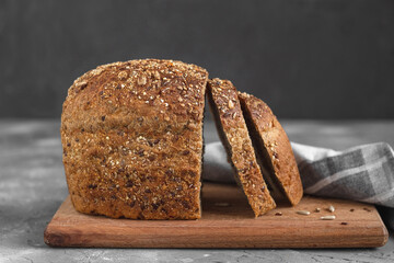 Fresh sliced rye bread on a wooden board. Healthy bread with seeds on a grey background.