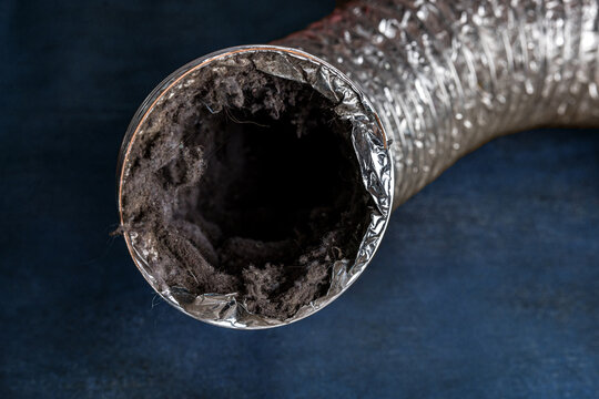 A dirty laundry flexible aluminum dryer vent duct ductwork filled with lint, dust and dirt against a blue background