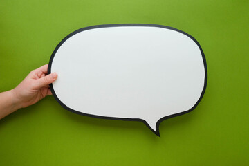 Speech bubble in hand on a green background. Comic cloud with a place for text