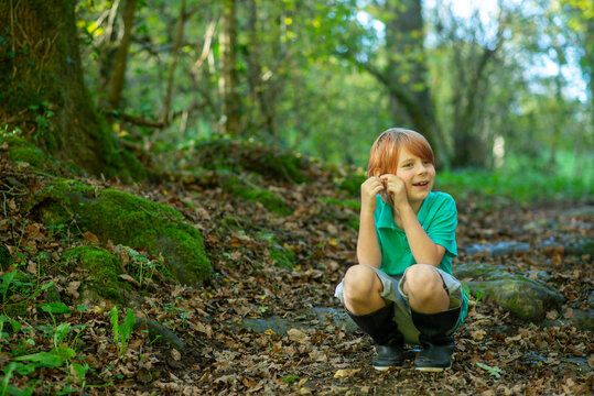 a boy of nine sits on a path in the woods alone