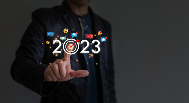 Man is pointing finger to year 2023, Like icon, heart smiley shocked and little lights surround year 2023, goal setting concept for coming new year.