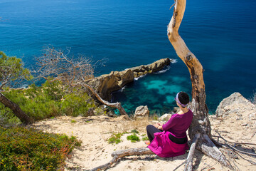girl sunbathes on top of a cliff with a beach in ibiza