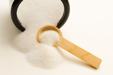 Spilled sugar from jar and wooden spoon