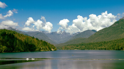Fluffy white clouds over mountains backing Cleveland Dam in North Vancouver, BC.