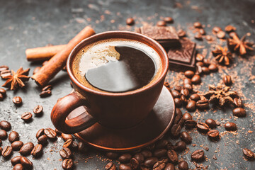 Fresh brewed black coffee in a cup on dark background with coffee beans and chocolate pieces