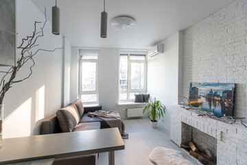 Interior of the modern loft kitchen-studio in the apartment. Room, furniture, sofa near wooden fireplace
