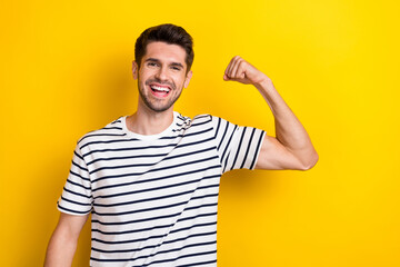 Portrait of cheerful nice person beaming smile arm flexing showing biceps isolated on yellow color background