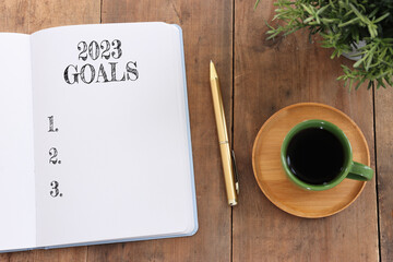 Business concept of top view 2023 goals list with notebook, cup of coffee over wooden desk