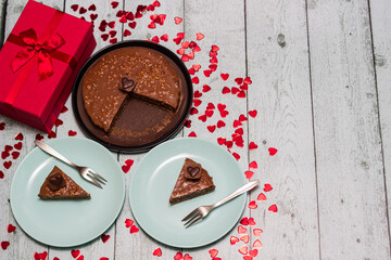 Chocolate cake served for two with gift for Valentine's Day. On wooden rustic table
