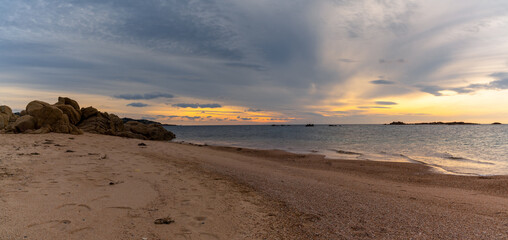 Fototapeta na wymiar panorama view of a golden sand beach at sunset with calm ocean water and red granite rocks