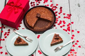 Chocolate cake served for two with gift for Valentine's Day. On wooden rustic table