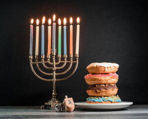 Hanukkah with eight lit candles, two dreidels and donuts on a plate. Jewish holidays (101)