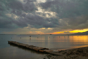 Fototapeta premium Abandoned boat platform in the Ebro Delta with a sunset in Tarragona, Spain.