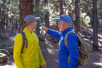 Senior grandfather and young grandson hiking together in the woods sharing the same passion for nature and healthy lifestyle.