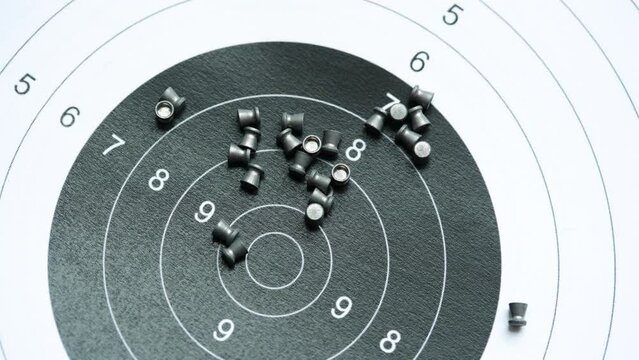 Simple shooting target and lots of metal pellets laying on top of it, object closeup, detail, nobody. Airguns, sport. Pellet ammo, air gun ammunition, range aim training, practice concept, no people