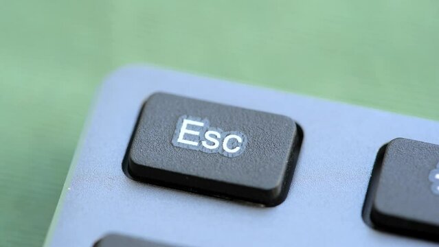 Man pressing an escape key on a modern office computer keyboard, object detail, macro, extreme closeup. Canceling, stopping an action, quitting, escaping a sequence simple abstract concept shot