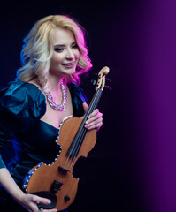 Fototapeta premium beautiful blonde girl playing violin in neon light on background