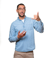 Hesitant young man making a gesture of calling with the hand