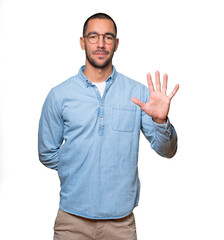 Young man making a number five gesture