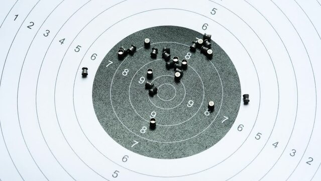 Circle shooting target and lots of metal pellets laying on top, object closeup, detail, nobody. Airgun sports, accessories. Pellet ammo, air guns ammunition, range aim training concept, no people