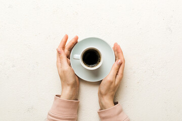 Minimalistic style woman hand holding a cup of coffee on Colored background. Flat lay, top view cappuccino cup. Empty place for text, copy space. Coffee addiction. Top view, flat lay