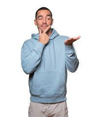 Fototapeta premium Doubtful young man holding something with his hand