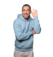 Happy young man smiling and making a gesture of trying to hear something