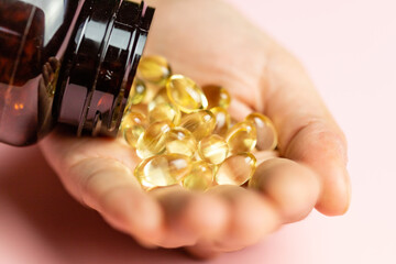 Vitamin D3 capsules poured out of the package. Care for health and immunity. A woman's hand. - obrazy, fototapety, plakaty