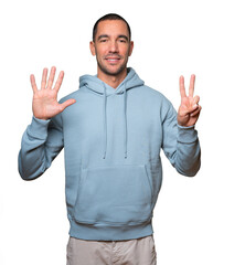 Happy young man doing a number seven gesture with his hands