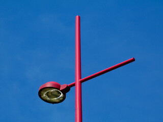 red color round halogen metal street lamp head with glass lens under blue sky. abstract perspective...