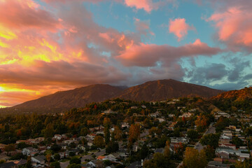 aerial shot of majestic mountains with powerful clouds and blue sky with homes, apartments and lush...