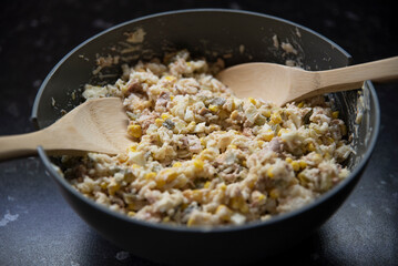 Sałatka z tuńczyka w dużej szarej misce z drewnianymi łyżkami do mieszania © Katarzyna