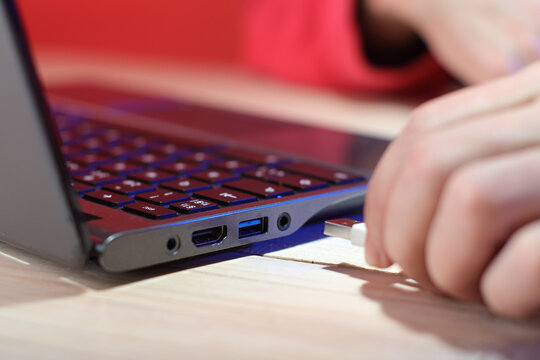 inserting a usb cable into a laptop on a table