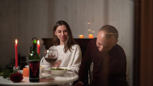 Couple having romantic dinner in restaurant, view through window, celebrating Valentine's Day