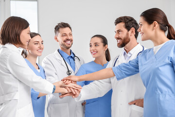 Team of medical doctors putting hands together indoors