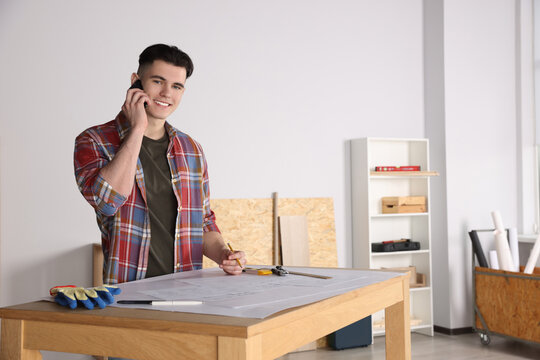 Young handyman talking on phone in room