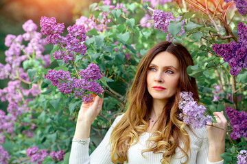 Banner with a beautiful girl looks into the distance in a blooming cherry garden. Spring and flowering of nature. Fashion and beauty concept. Copy space on the left